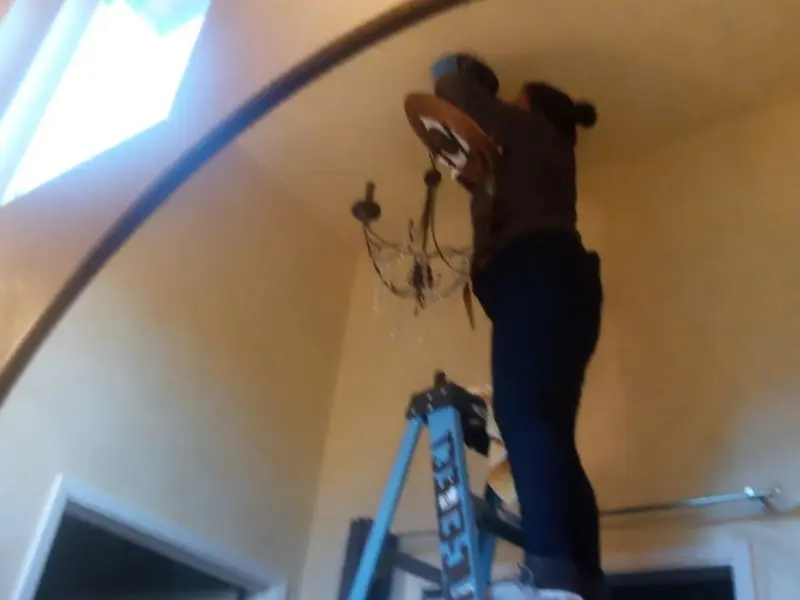 Electrician installing a chandelier in a Akron residence